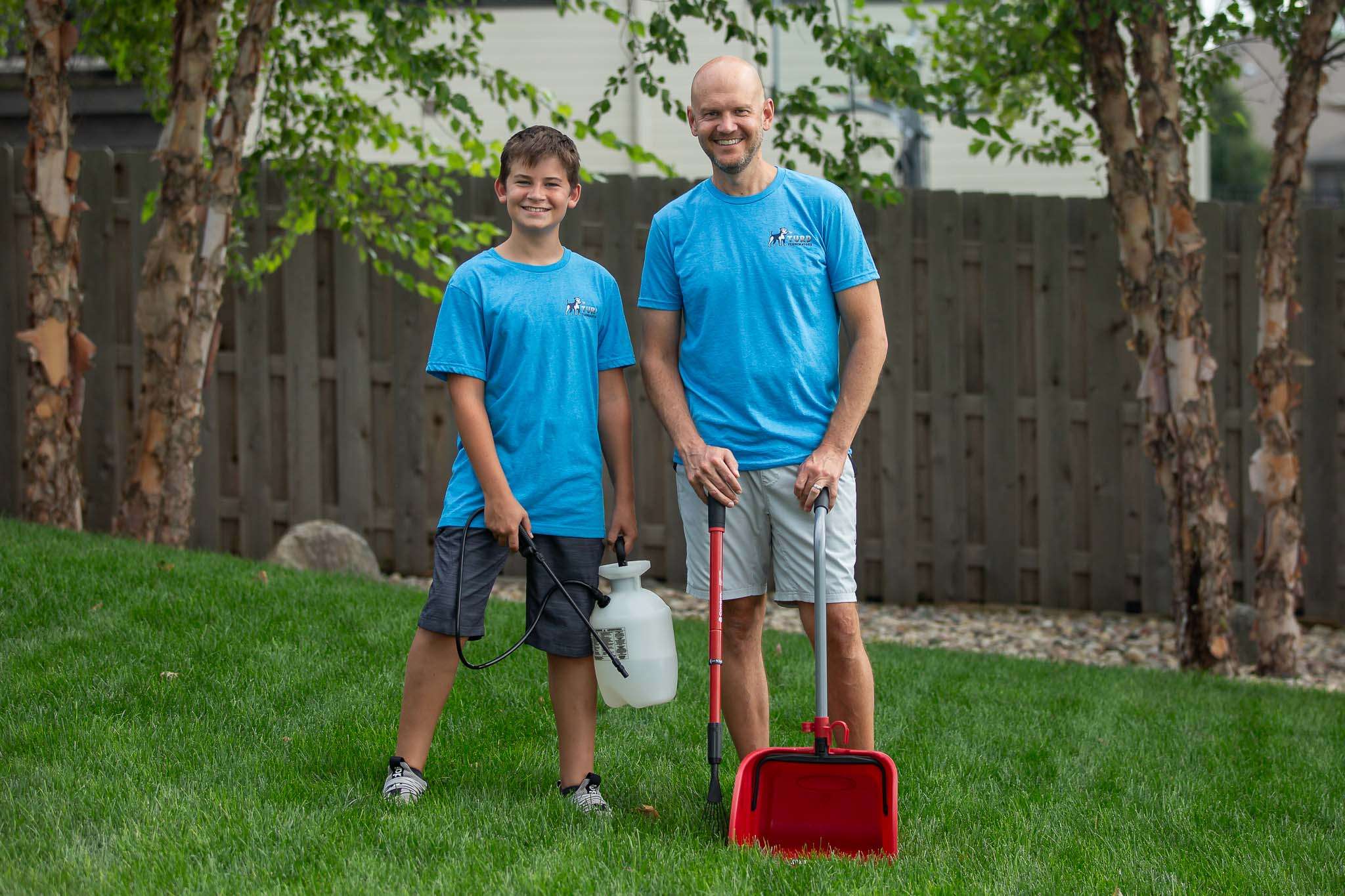 Father and son team, Michael and Daniel, in a freshly cleaned yard with pet waste removal equipment.