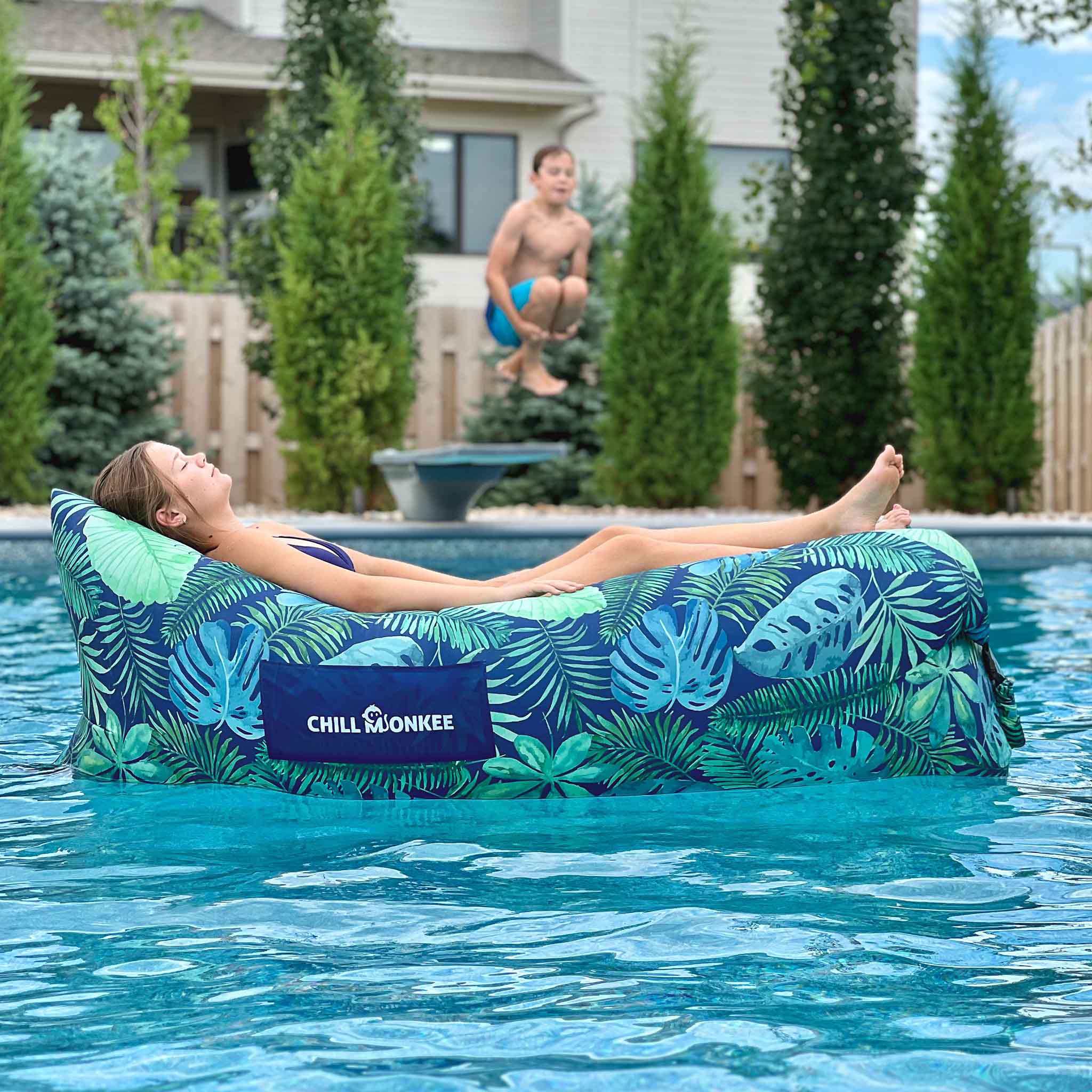 Girl relaxing on a pool float while a boy jumps off a diving board, symbolizing free time gained by skipping dog poop cleanup.